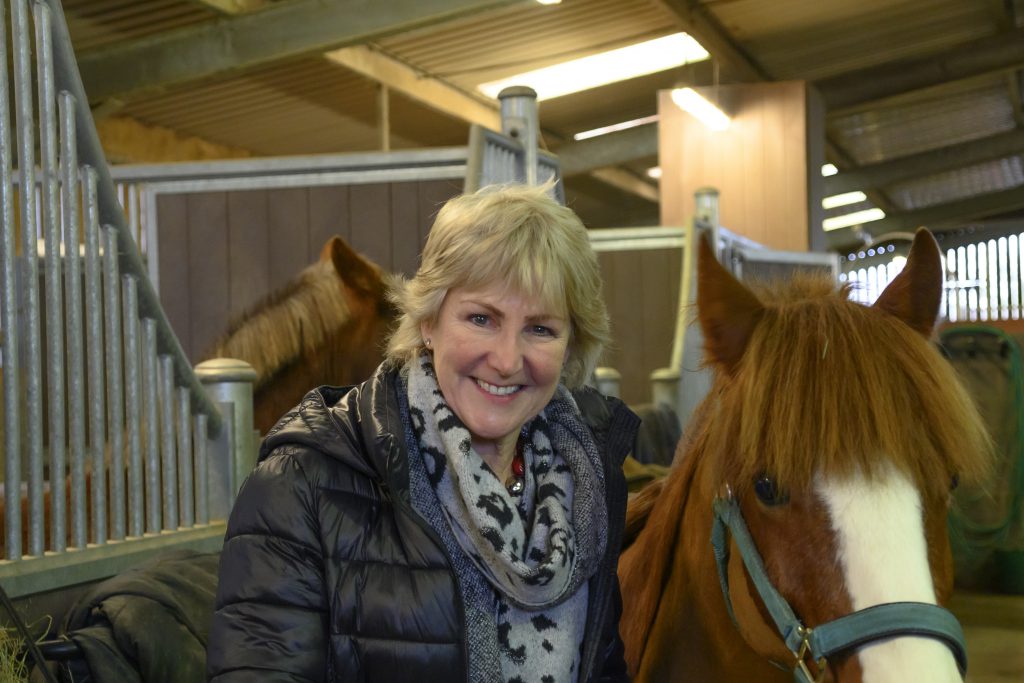 member of the trustee board stood in a barn next to a chestnut pony
