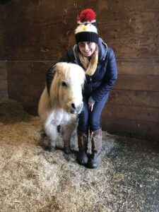 woman stood next to a palomino shetland pony in a stall