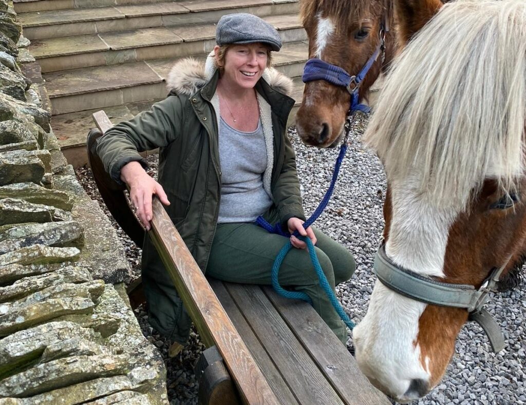 member of the trustee board sat on a bench holding two ponies