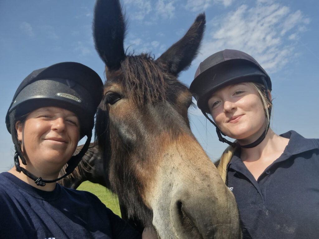 Selfie of two members of staff stood either side of a brown mule