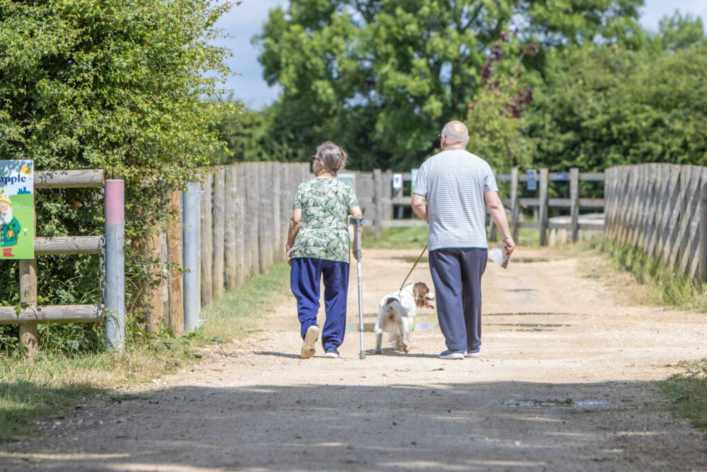 an older couple walking their dog along a walkway at Bransby Horses