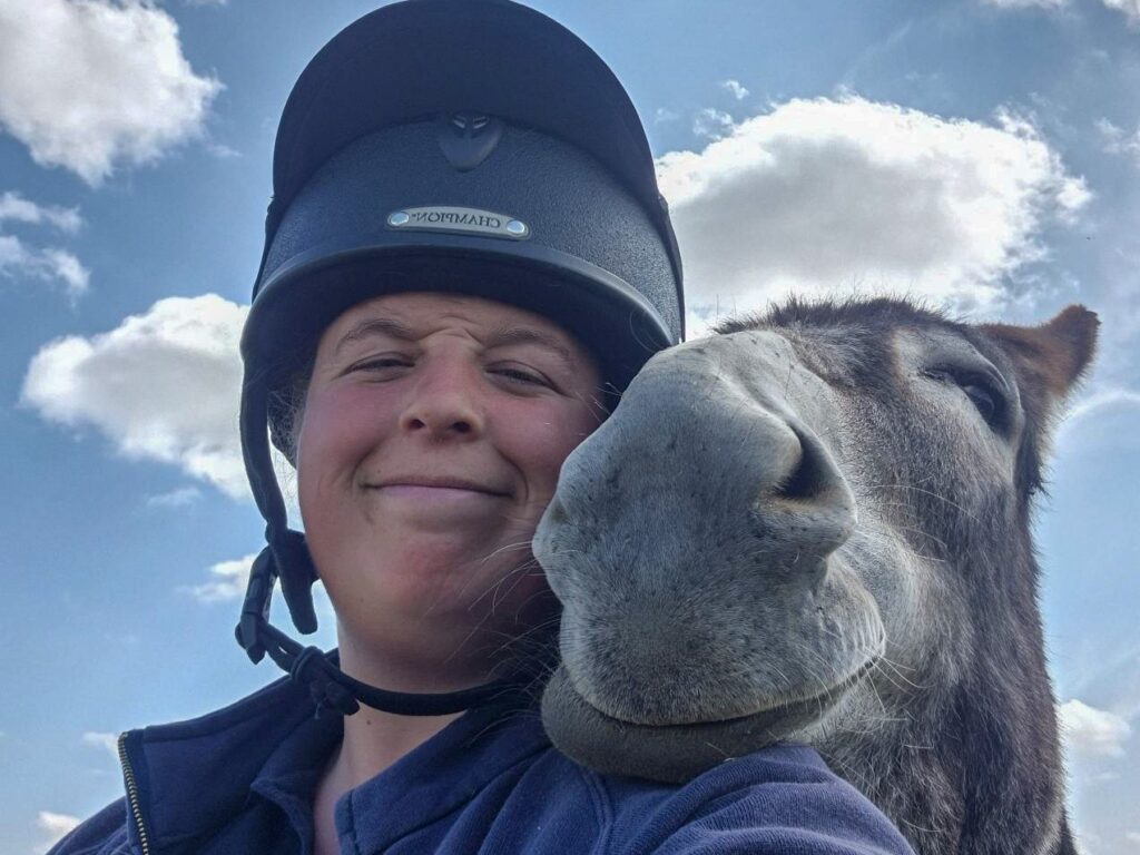 a yard team member with a donkey's head resting on her shoulder